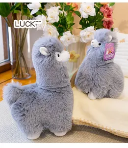 Macro view of two soft grey plush alpaca dolls presented in a cozy and warm indoor setting