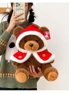 Close-up of a brown teddy bear wearing a red Christmas hooded cape with Merry embroidery