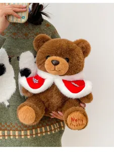 Cute brown teddy bear plush toy wearing a festive red Christmas cape with fur trim