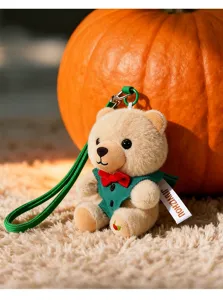 Macro opname van een kleine pluche teddybeer met groen vest en een rode strik