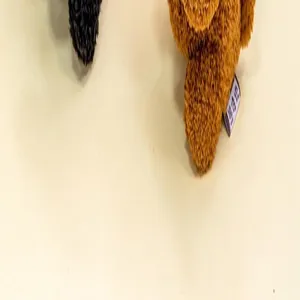 Close-up view of a brown plush puppy pendant showing its soft fur texture and a product tag