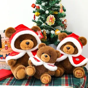 Set of three brown plush teddy bears wearing red Christmas capes on a festive plaid cloth.