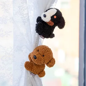 Pair of cute plush dog charms decorating a white lace curtain in soft daylight