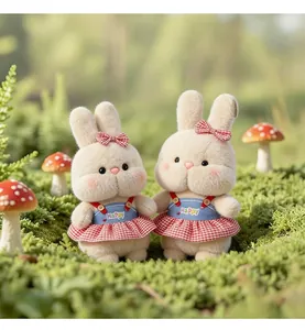 Detail view of two cute plush rabbits wearing red checkered dresses in a mossy scene