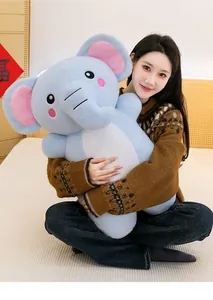 Dettaglio di un grande peluche a forma di elefante blu tenuto da una modella a letto