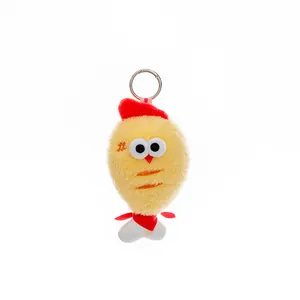 Close-up of cute yellow plush chicken keychain with red hat and scarf