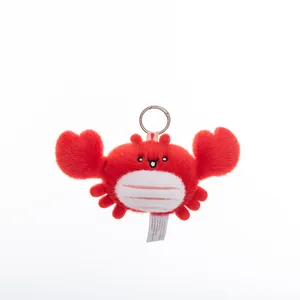 Detail of a cute red plush crab keychain with soft fur and a silver metal ring