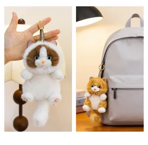 Close-up detail of a cute fluffy cat plush keychain shown hanging on a grey backpack