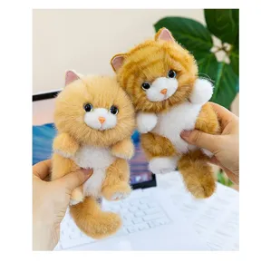 Detail of fluffy ginger and white kitten plush toys held in hands as cute pendants
