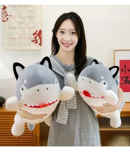 Cheerful young woman holding two creative grey and white shark-dog hybrid plush toys