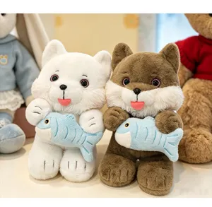 Close-up of white and brown cat plush toys holding blue fish