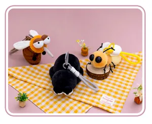Detailansicht süßer Insekten-Plüschanhänger auf gelb-weiß kariertem Stoffhintergrund.