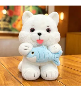 Close-up of a cute white fluffy cat plush toy holding a small blue fish on a wooden table.