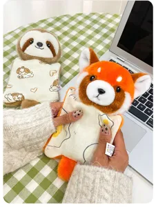 Detail shot of a cute red panda and sloth plush toy pendant held by hand on a table.