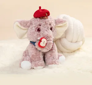 Close-up van een schattige roze olifantenknuffel met rode baret en een appelschijfje.