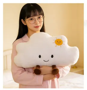 Cojín de peluche de nube blanca con cara sonriente y bordado de sol sostenido por una modelo