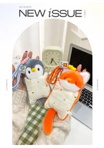 Close-up of cute penguin and fox plush keychain pendants held in hand on desk