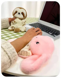 Adorable sloth and pink rabbit plush dolls used as soft wrist rests on a home office desk