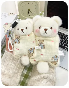 Detail shot of two cute white plush bear pendants featuring decorative patterned pouches