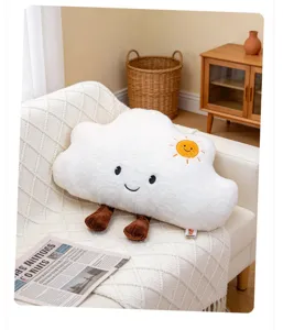 Cojín de peluche nube blanca con cara sonriente y bordado de sol en sofá acogedor