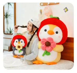 Detail shot of a cute penguin plush toy wearing a strawberry hat and holding a flower.