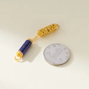 Detail view of gold filigree and lapis lazuli pendant accessory next to a coin for scale