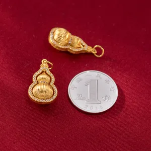 Detailed view of two gold-plated calabash pendants next to a coin for size reference.