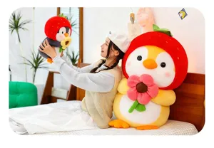 Young woman holding cute strawberry-themed penguin plush toys in a bright bedroom setting.