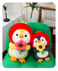 Two cute penguin plush dolls with strawberry hats and flowers on a green chair