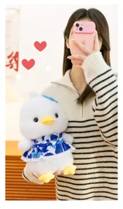 Close-up detail of a soft white plush duck toy wearing a blue floral dress with a bow
