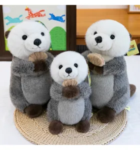 A group of three adorable sea otter plush toys in different sizes on a round woven mat