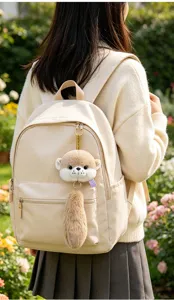 Detailed view of a plush raccoon animal keychain hanging on a beige campus backpack