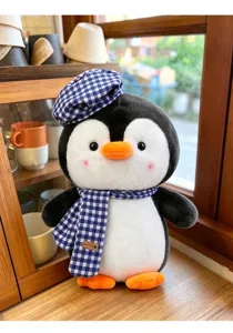Detailansicht eines Pinguin-Plüschtiers mit blau karierter Baskenmütze und Schal im Regal