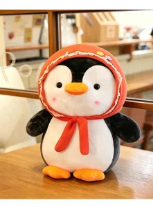Detailaufnahme eines süßen Pinguin-Plüschtiers mit einem orangefarbenen Kapuzenschal