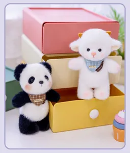 Detail von süßen Panda- und Schaf-Plüschanhängern mit Lätzchen in farbenfroher Umgebung.