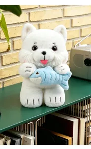Macro view of a cute white plush cat toy holding a small blue fish on a green shelf