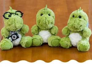 Tres lindos peluches de dinosaurios verdes sentados con gafas y detalles de cámara.