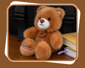 Close-up of a fluffy brown teddy bear plush keychain with a Happy leather tag pendant