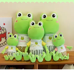 Cute green frog plush toys in various sizes wearing striped clothes on a wooden shelf.