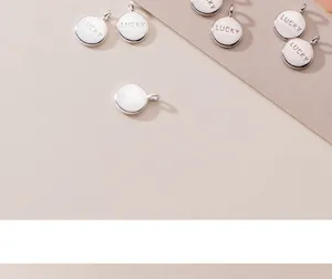 Close-up of small silver round charms with 'LUCKY' engraving for DIY jewelry projects
