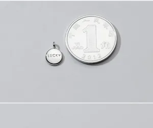 Detailed view of small S925 silver round pendant with 'LUCKY' engraving for size reference
