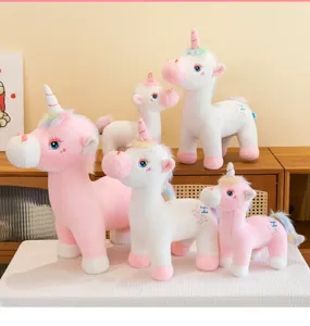 Group of soft white and pink unicorn plush toys in various sizes with rainbow manes.