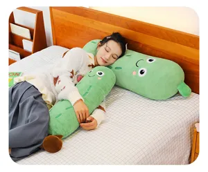 Großes weiches grünes Gurken-Plüschtier als langes Kissen zum Schlafen und Kuscheln im Bett.