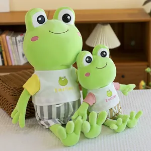 Pair of cute green frog plush toys wearing striped shorts in a cozy home interior