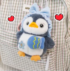 Close-up of a cute plush penguin keychain with a blue bow hanging on a backpack