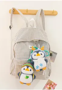 Detailed view of two cute penguin plush keychains hanging on a checkered backpack.