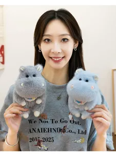 Young woman holding two cute grey and blue plush hippo doll keychains.