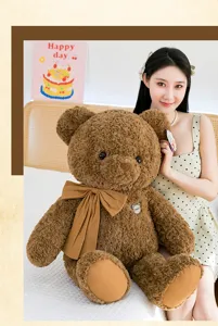 Grande peluche ours en peluche marron avec un joli nœud papillon tenu par un mannequin