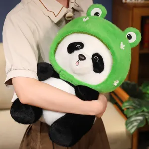 Süße Panda-Plüschpuppe mit grüner Froschkapuze, gemütlich im Arm gehalten zu Hause
