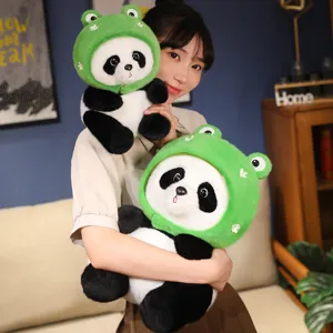 Niedliche Panda-Plüschpuppe mit grünem Froschhut, gehalten von einer Frau im Wohnzimmer.